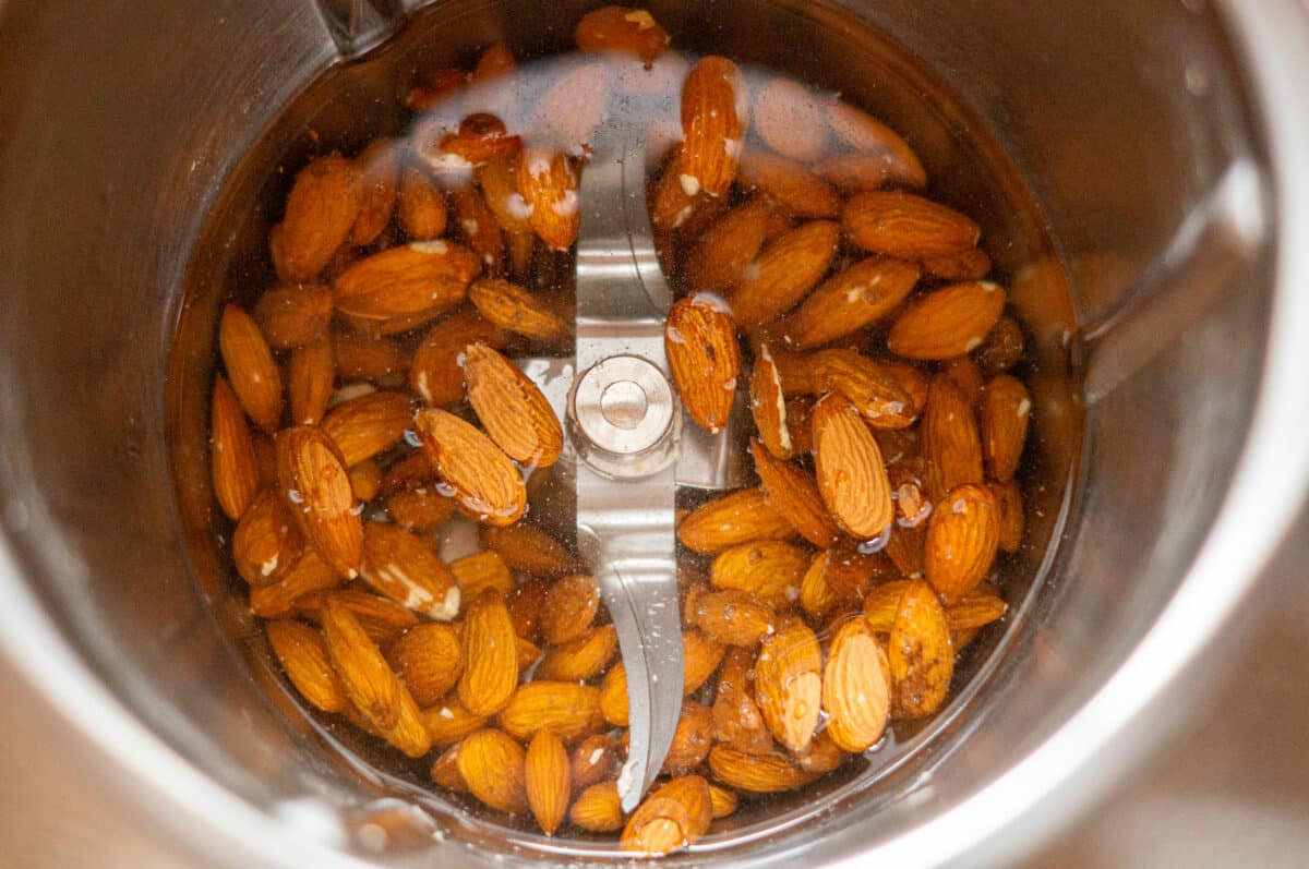 Almonds in the mixing bowl of the Thermomix® with water, cooked on reverse direction speed 1