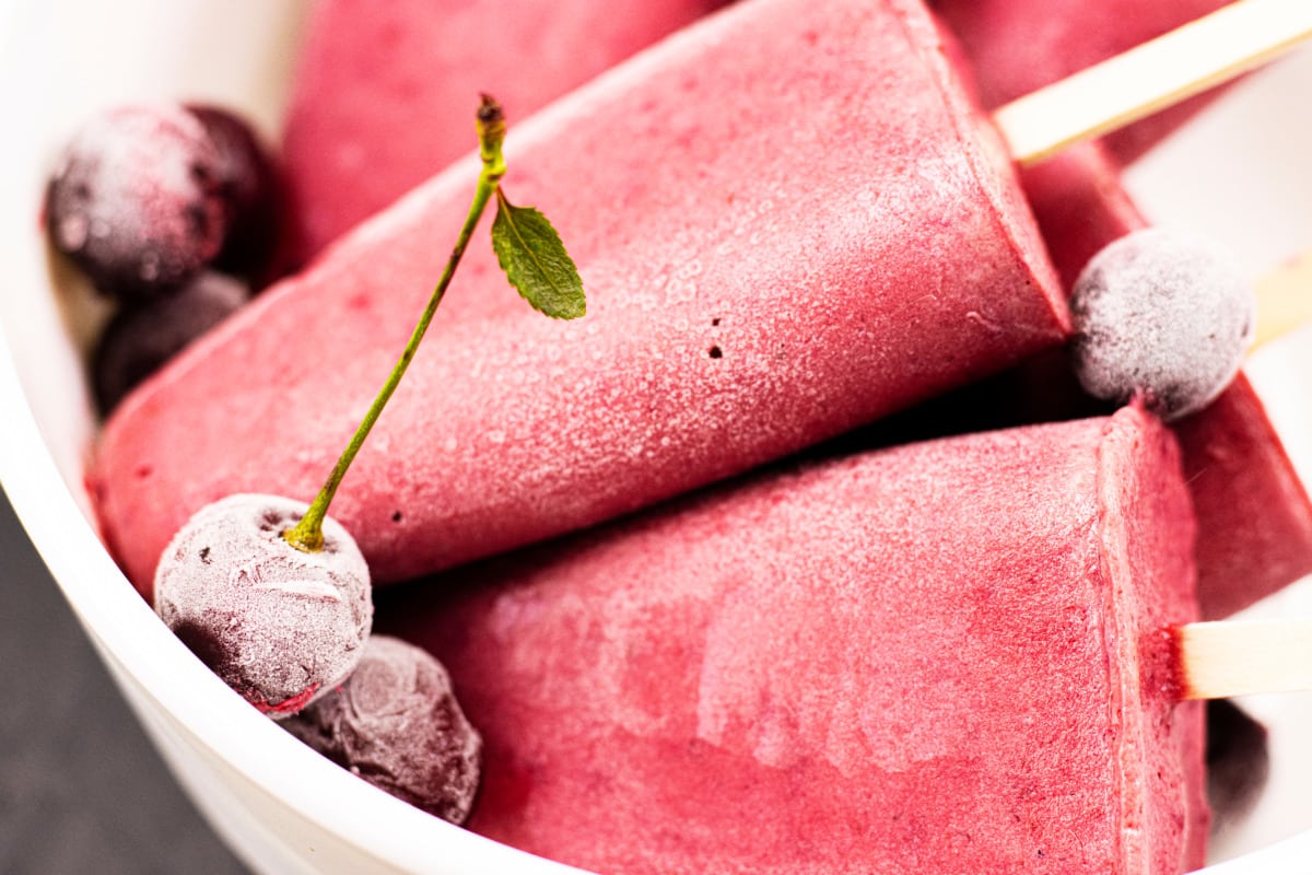 Cherry ice lollies made with the Thermomix® on a stick, arranged on a plate