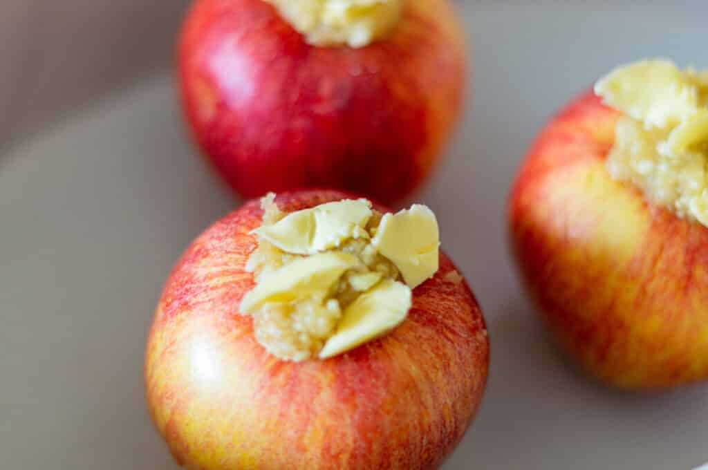 Fill the baked apples, add butter on top and place them in an ovenproof dish