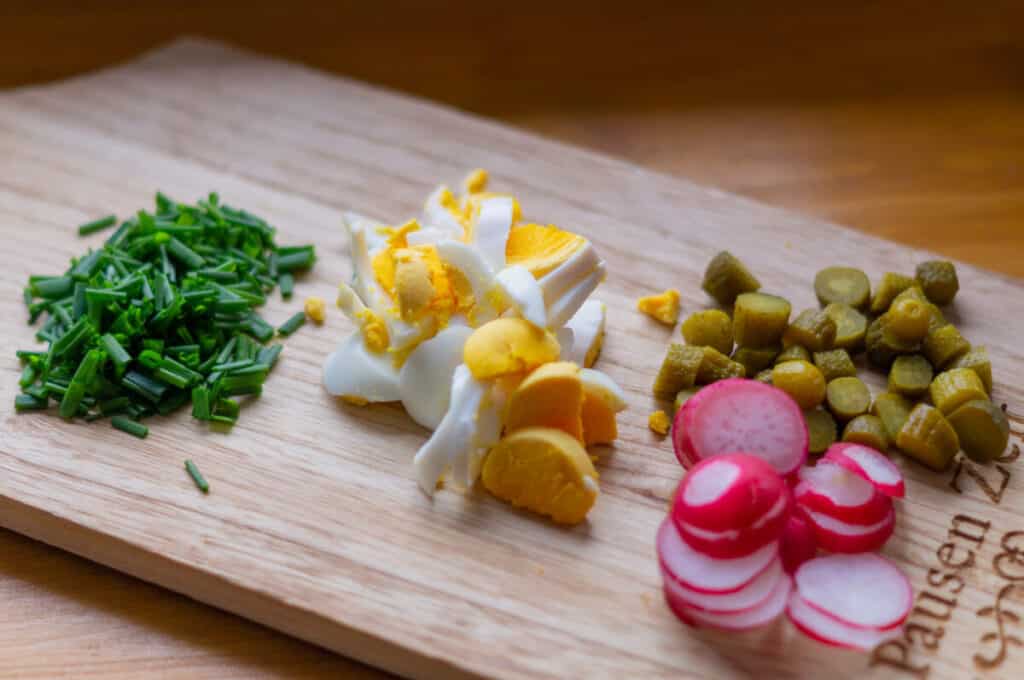 Cutting chives, eggs, radishes and pickled gherkins