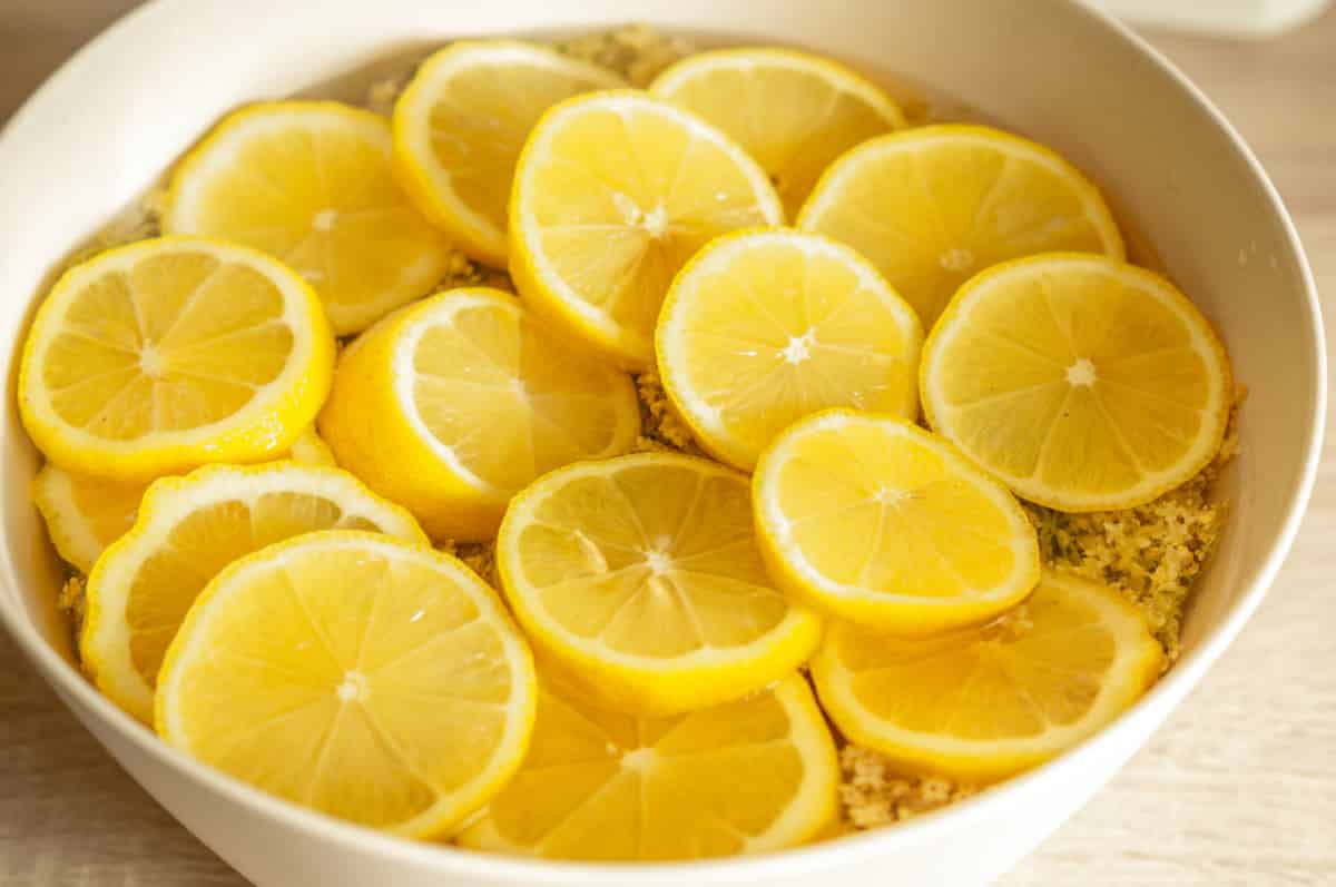 Pouring sugar syrup from the Thermomix® over lemons and elderflower heads