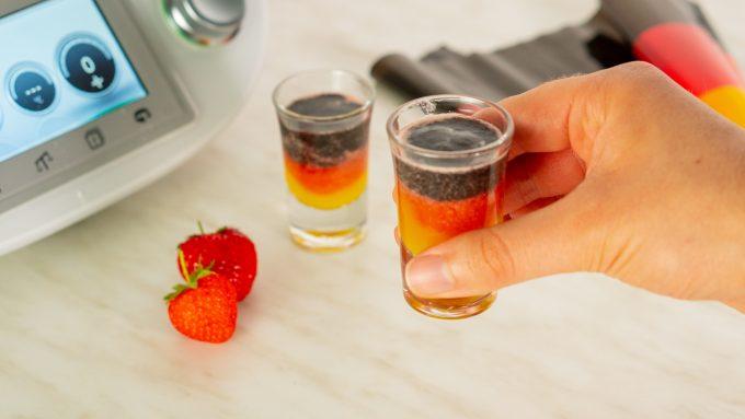 Football shots made with the Thermomix® served and ready, group holding shot glasses up to the camera
