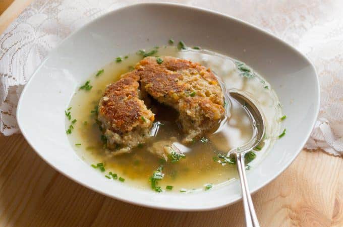 Kaspressknödel floating in a clear beef broth as a soup garnish