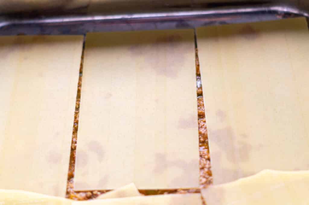 Lasagne sheets being placed between the layers from the mixing bowl