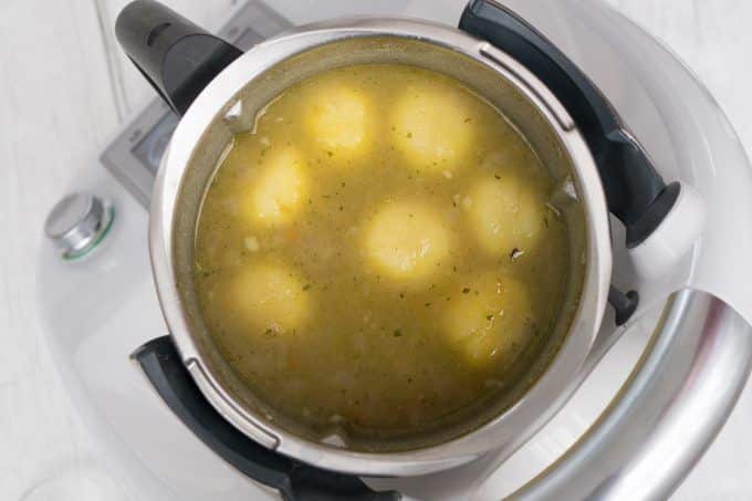 Potatoes and vegetable stock in the Thermomix® mixing bowl before cooking