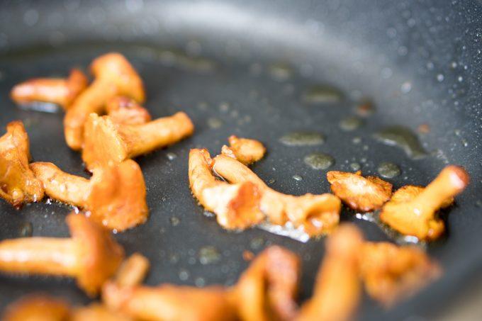 Chanterelles being seared in a pan with olive oil over a high heat