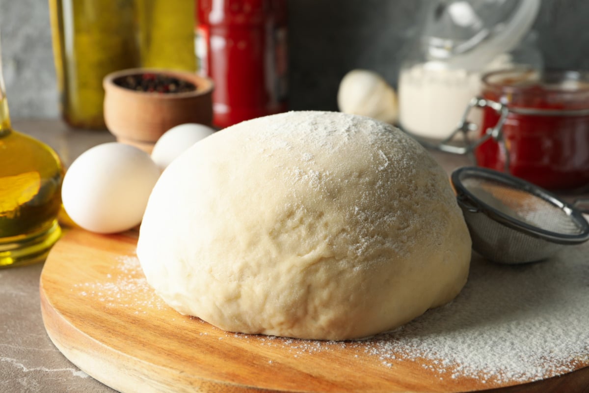 The quickest pizza dough from the Thermomix® rolled out and topped, ready to bake