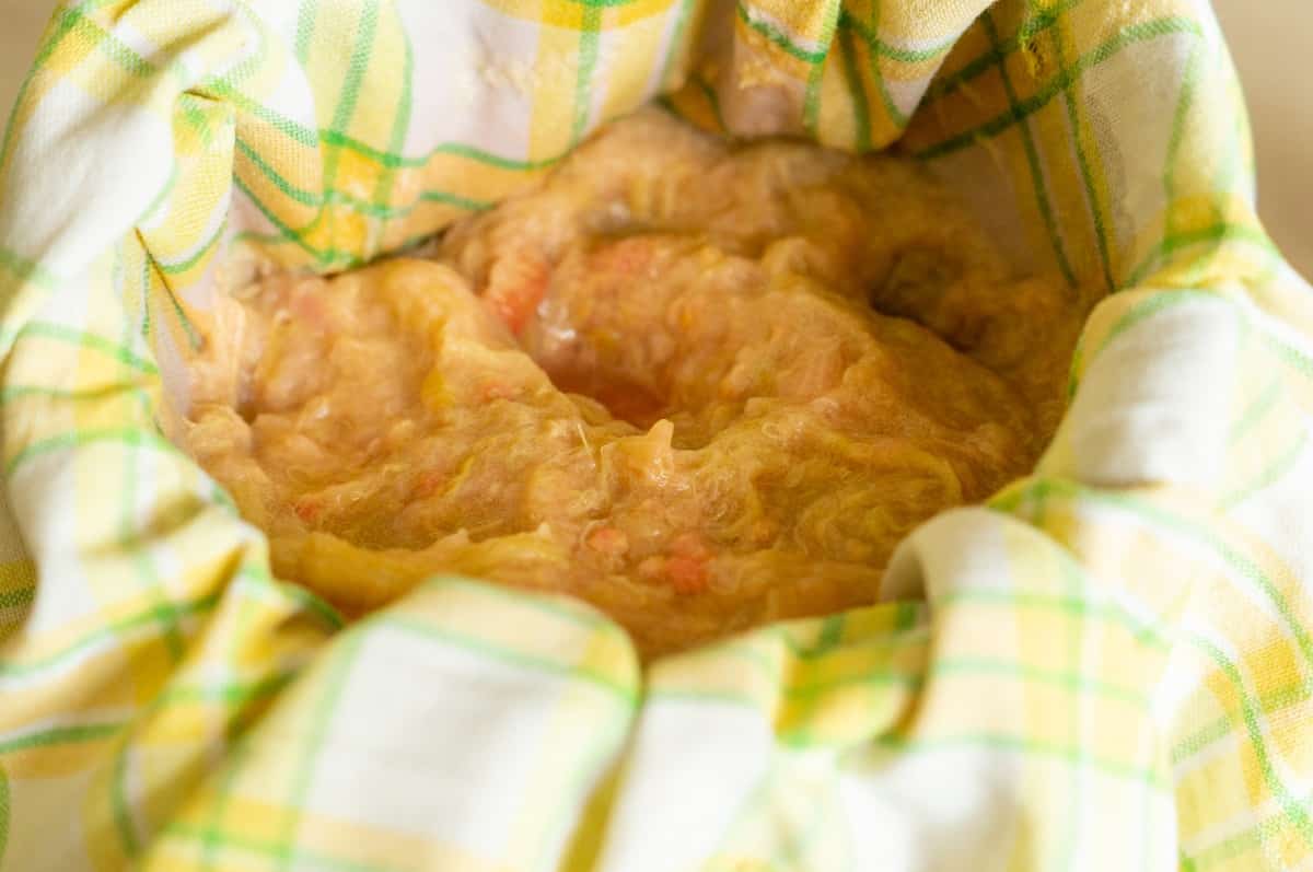 Cooked rhubarb being strained through a tea towel