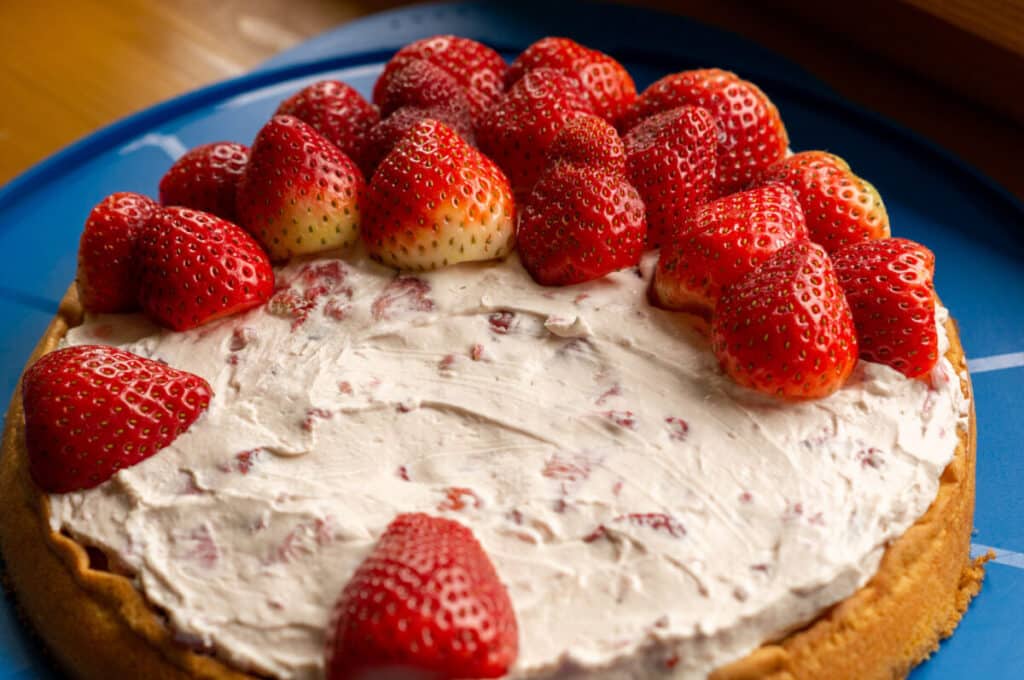 Halved strawberries being placed point-side up on the mascarpone cream