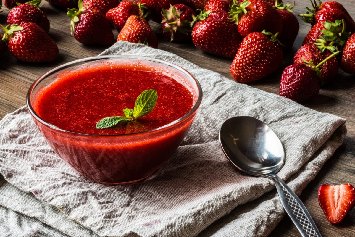 Thermomix® strawberry sauce being poured over vanilla ice cream