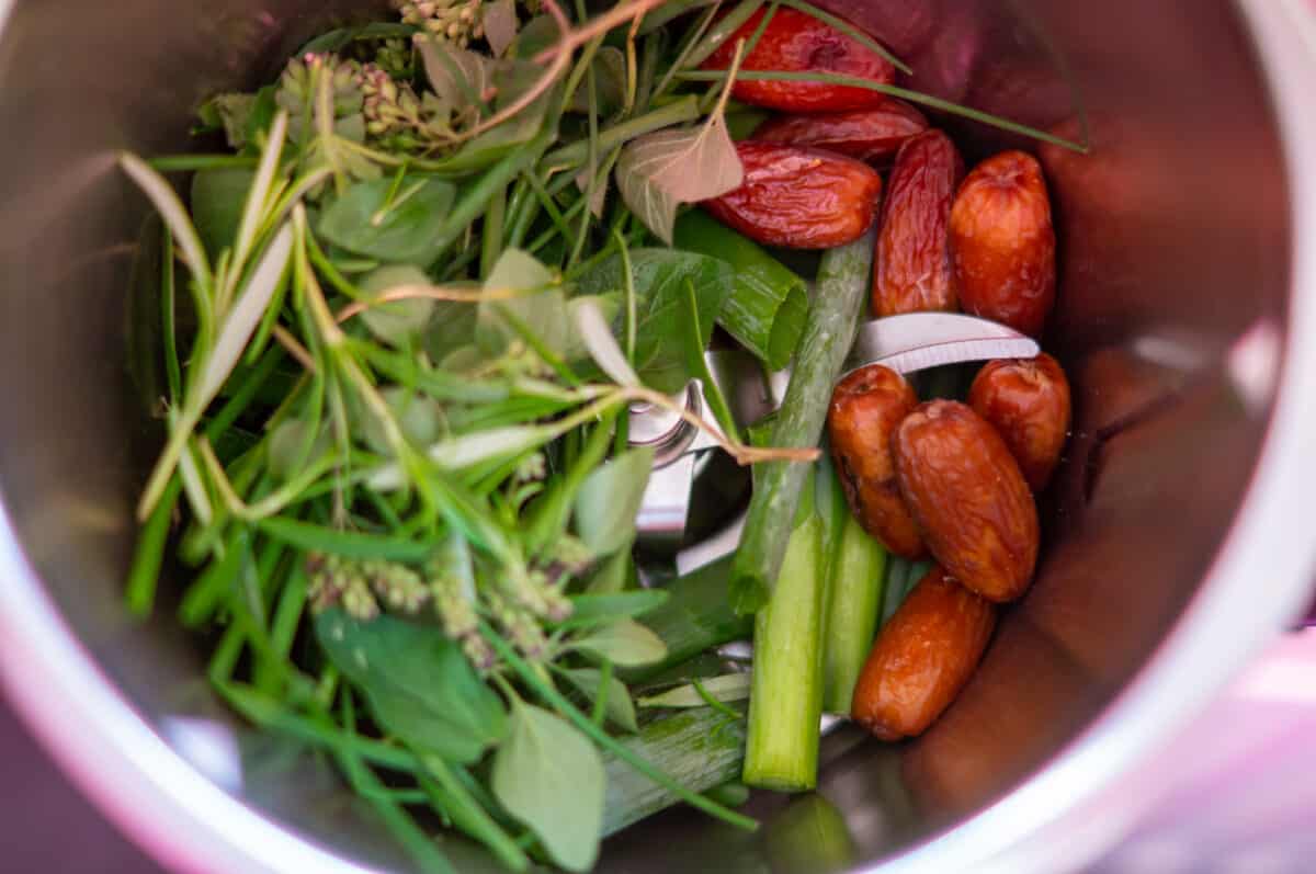 Spring onions, herbs and dates placed in the mixing bowl ready to chop